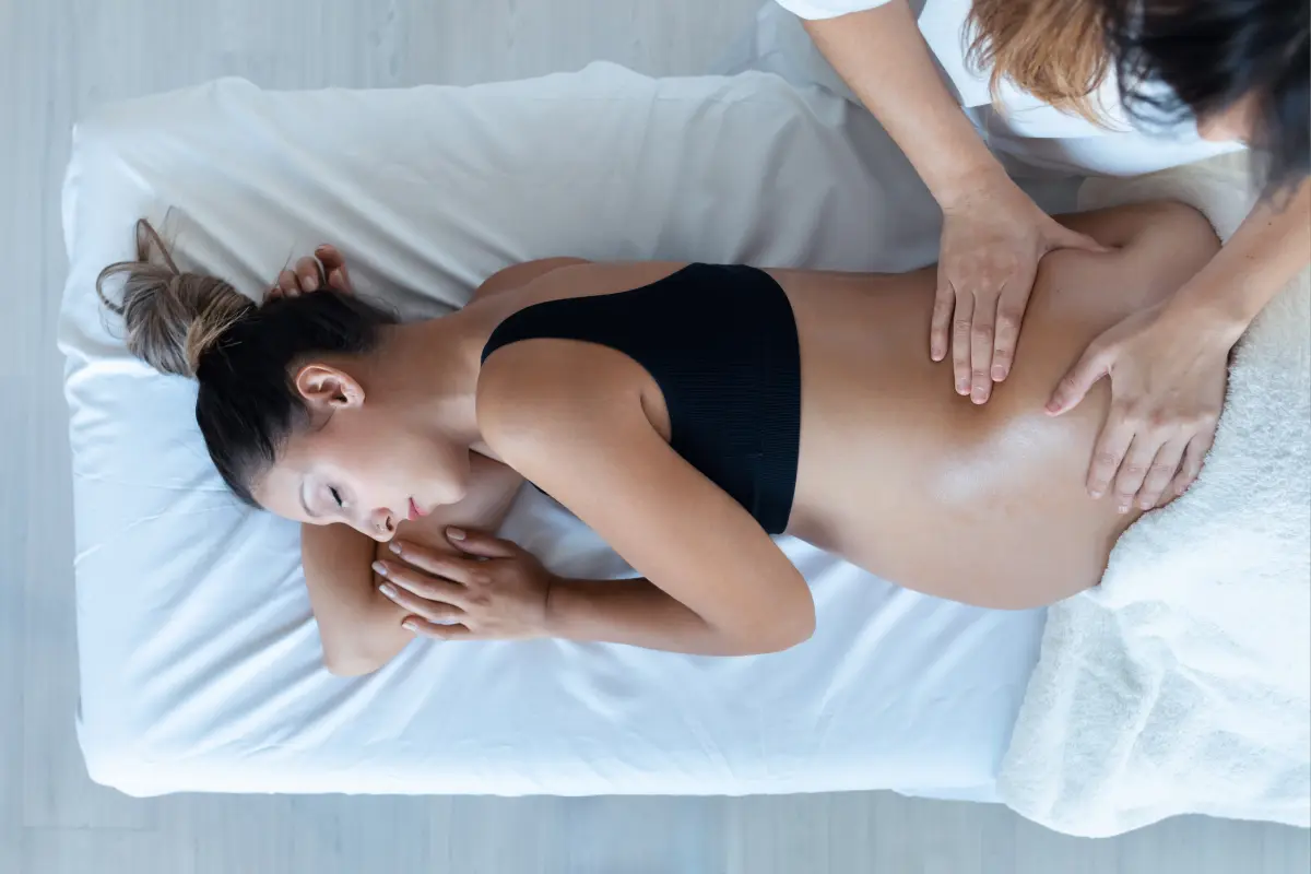 A woman is getting her belly rubbed by another person.
