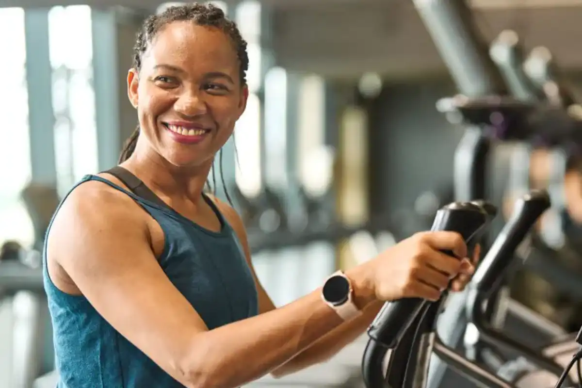 A woman is smiling while using an exercise machine.